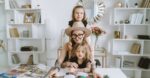 A mother and her two daughters enjoy reading a magazine together in a cozy home setting.
